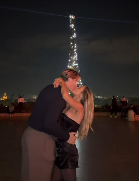 Couple kissing with the Eiffel Tower in the background.