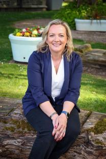 Woman sitting on a log, smiling.