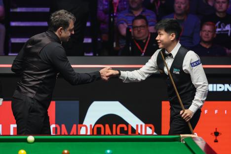Zhao Xintong and Ronnie O'Sullivan shaking hands before a snooker match.