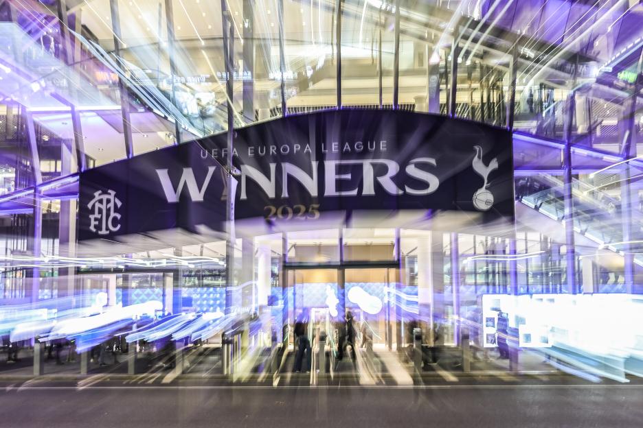 FC Copenhagen fans cheering in the stands, holding up team scarves.