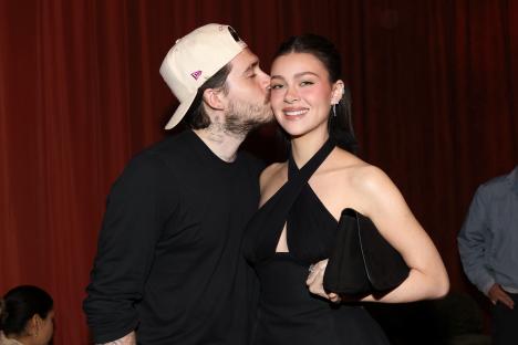 Brooklyn Beckham kissing Nicola Peltz Beckham on the cheek.