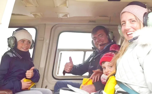 Family giving thumbs up in a helicopter.