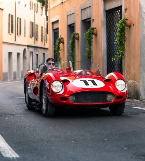 Red Ferrari 250 Testa Rossa driving down a street.