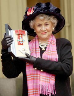 Joan Plowright holding her Damehood insignia at Buckingham Palace.