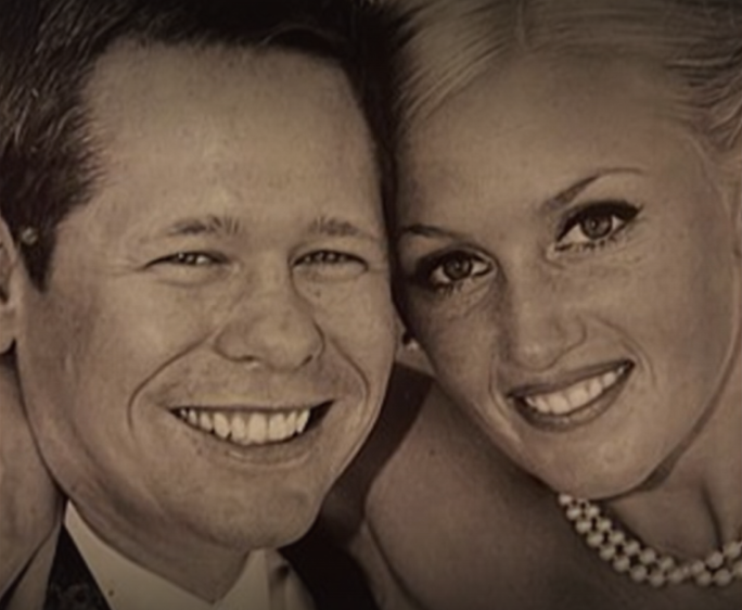 A man and a woman smiling, in a black and white photo.