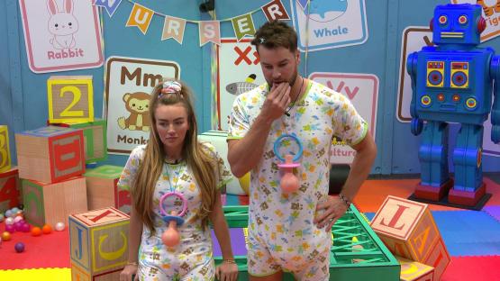 Chris Hughes and Ella Rae Wise in baby onesies on a television show set.