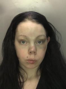 Mugshot of a woman with long dark hair and facial bruising.