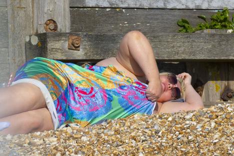 Woman lying on a beach in a patterned dress.