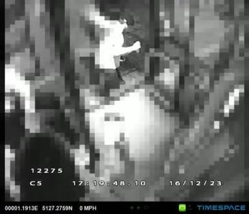 Low-resolution security camera footage of a person appearing to punch another person.