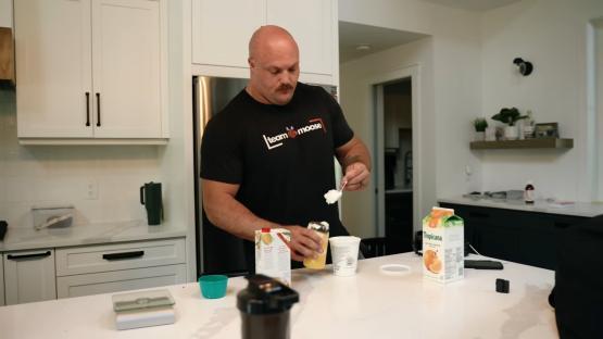 Greek yogurt being added to a jar of yellow liquid.
