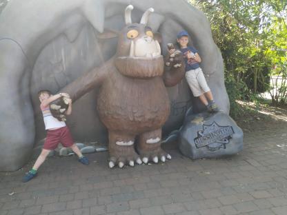 Two boys posing with a large Gruffalo statue at Chessington World of Adventures Resort.