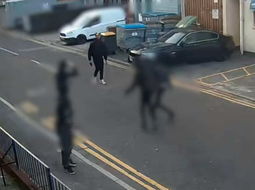 Three individuals and cars on a street.