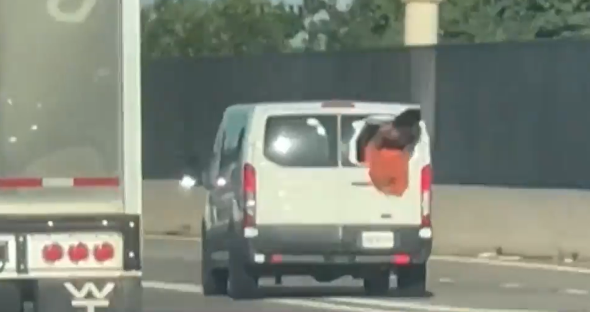 Person hanging out of a van window on a highway.