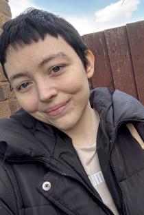 Photo of a young woman with short hair, wearing a black puffer jacket.