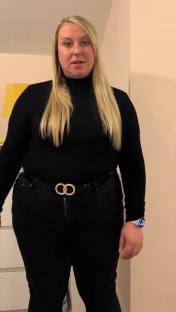 Woman in black turtleneck and jeans showing weight loss.