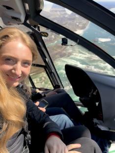 Woman in helicopter over ocean.