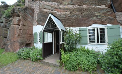 A rock house with a small front door and green shutters.