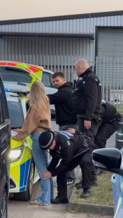 Police officers arresting a man and a woman.
