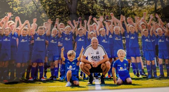 Photo of Rob Maul visiting Bergentheim, Netherlands, with a group of children in blue soccer uniforms.