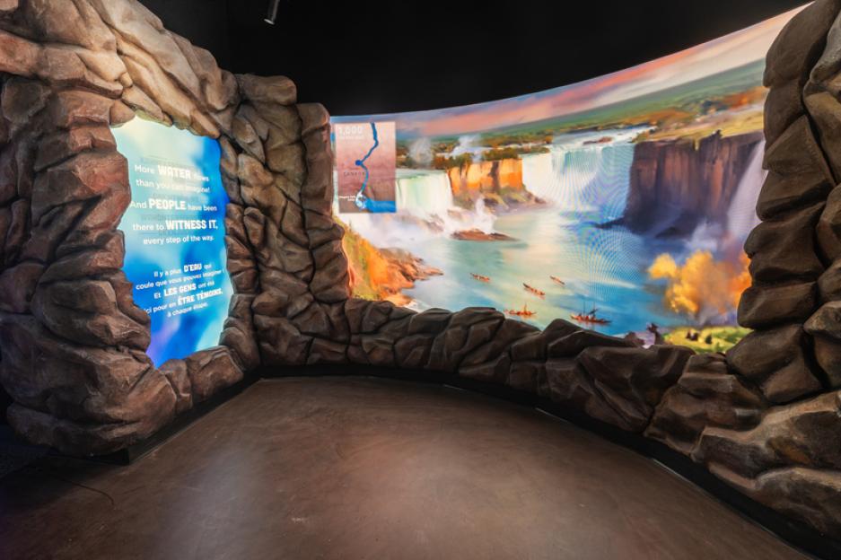 Interior of Niagara Takes Flight ride featuring a large curved screen showing Niagara Falls and surrounding area.