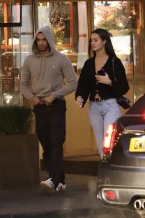 a man in a grey hoodie stands next to a woman in a black sweater