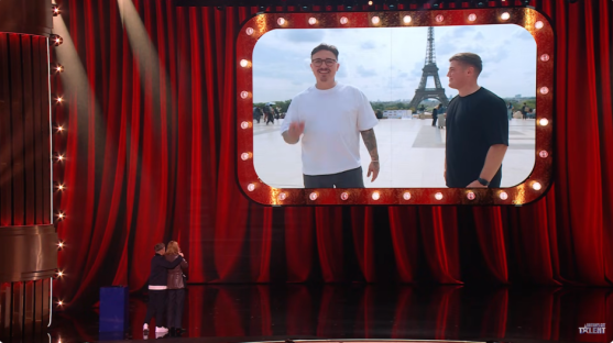 Harry Moulding on stage with a video screen showing him in Paris.