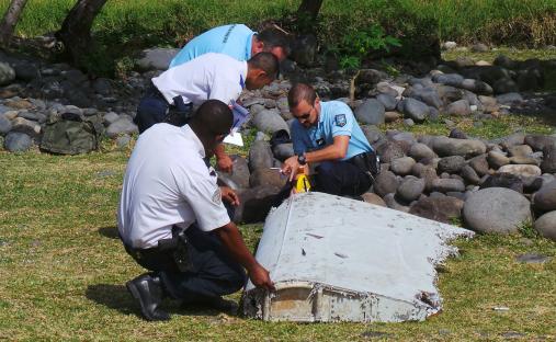 Investigators examining a piece of plane debris on a beach.