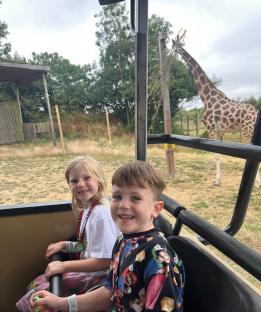 Two children on a safari ride, watching a giraffe.