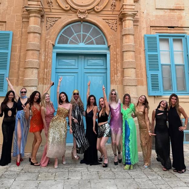 Group of women in party attire posing in front of a building.