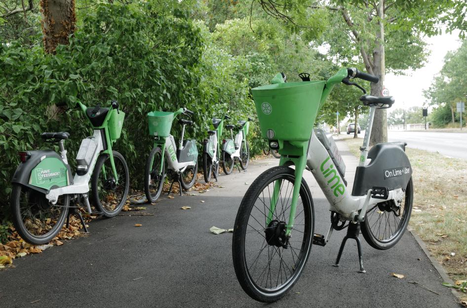Lime e-bikes parked by a tree.