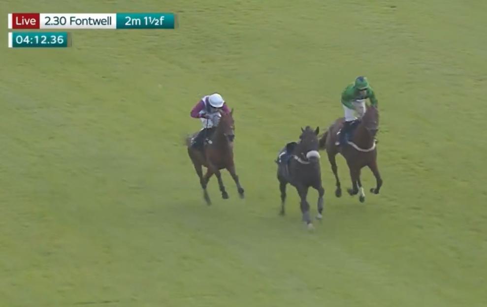 Three horses and jockeys racing on a green track.