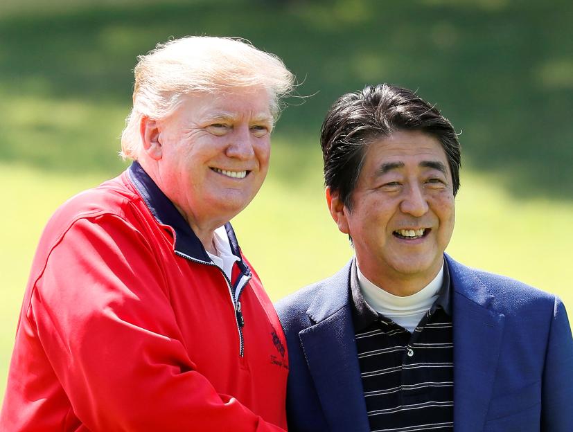 Former US President Donald Trump and former Japanese Prime Minister Shinzo Abe smiling during a round of golf.