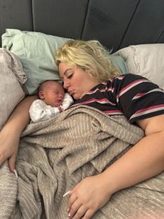 A mother sleeping with her newborn baby.