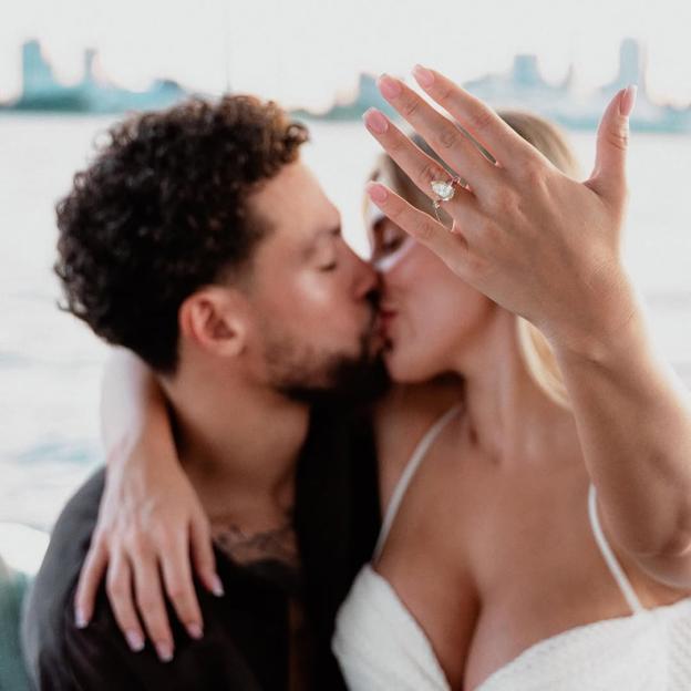 Elle Brown and her fiancé kissing, showcasing her engagement ring.
