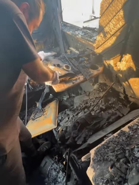 A person examining the fire damage inside a burned-out tour bus.