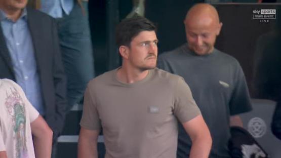 A man in a tan t-shirt stands with other people.