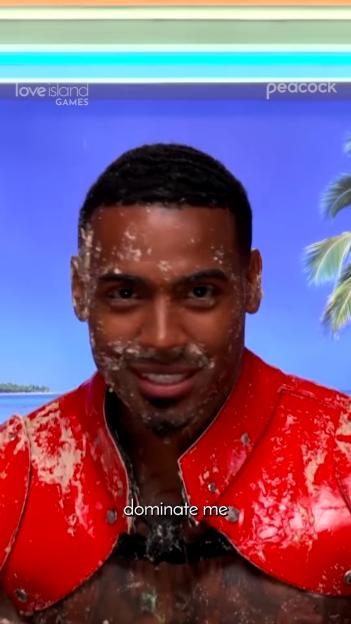 A man with a mess on his face and chest, wearing a red top, with text that reads "dominate me".
