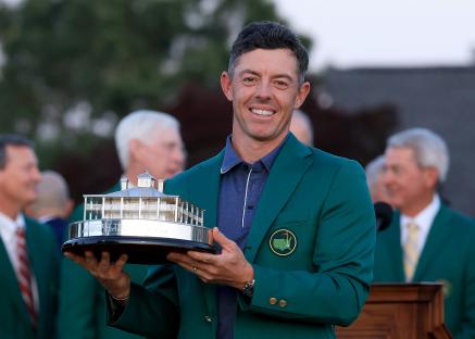 Rory McIlroy holding the Masters Tournament trophy in a green jacket.