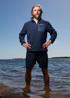 Angus Collins standing in shallow water, preparing for a solo row around Great Britain.