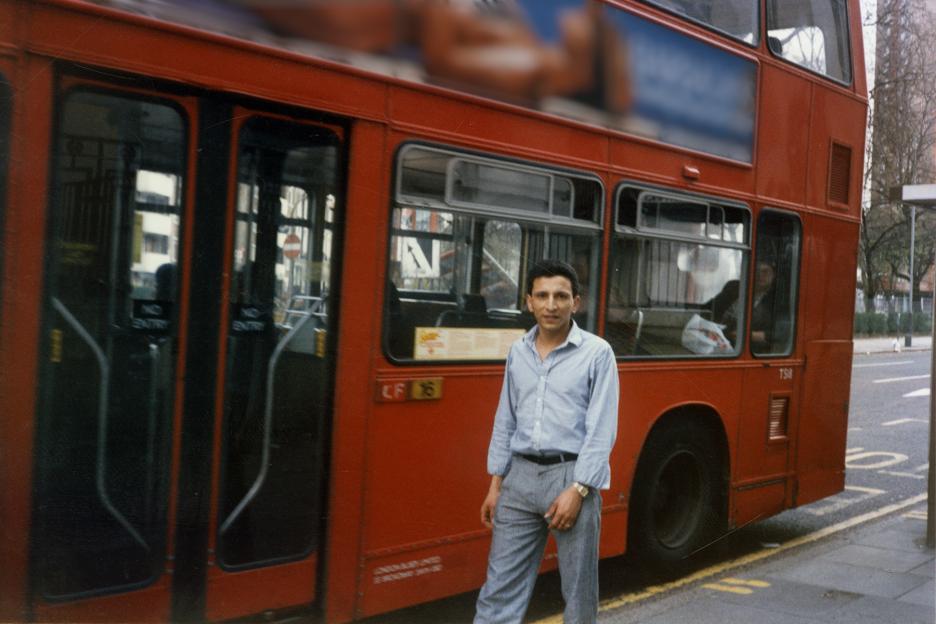 Man standing in front of a red double-decker bus.