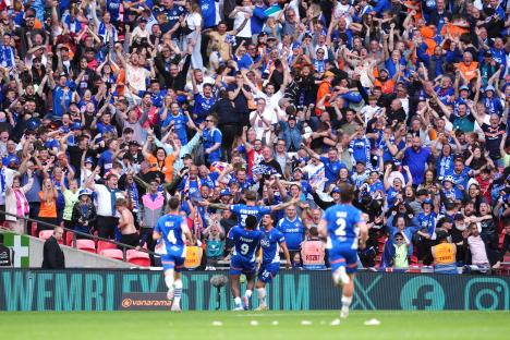 Oldham Athletic players celebrating a goal at Wembley Stadium, surrounded by cheering fans.