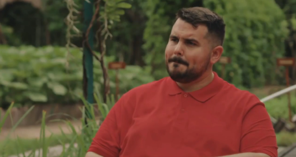 A man with a beard and mustache wearing a red polo shirt.