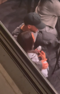 Ruben Dias and Maya Jama cuddling and kissing at a football match.