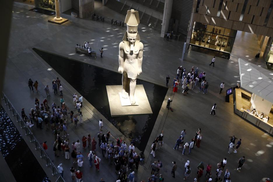 Aerial view of tourists gathered around a large statue of Ramesses II at the Grand Egyptian Museum.