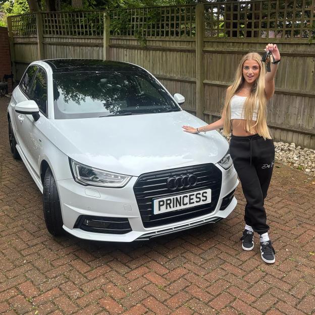 Woman holding car keys in front of her new white car.