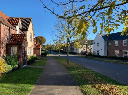 A paved walkway next to a row of houses on a sunny day.