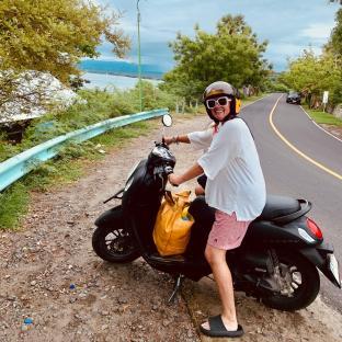Woman on scooter overlooking water.