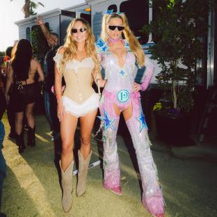 Two women in cowgirl outfits at a festival.