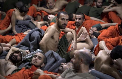 Men accused of being affiliated with ISIS sit on the floor of a Syrian prison.