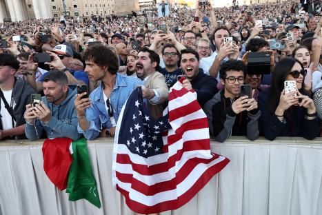 Crowd of people using phones to photograph the announcement of a new pope.